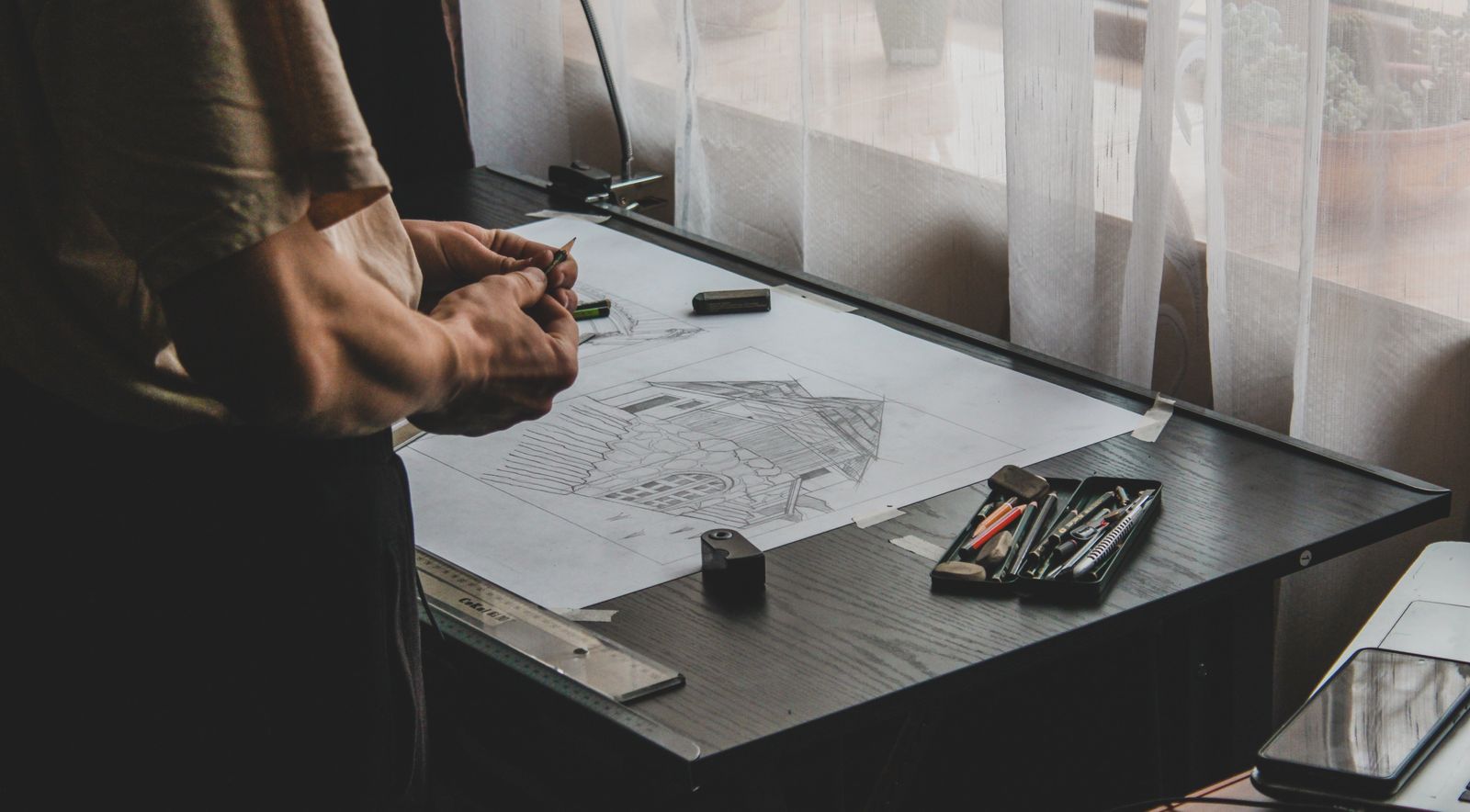 Architect's hand sketching a building elevation on paper
