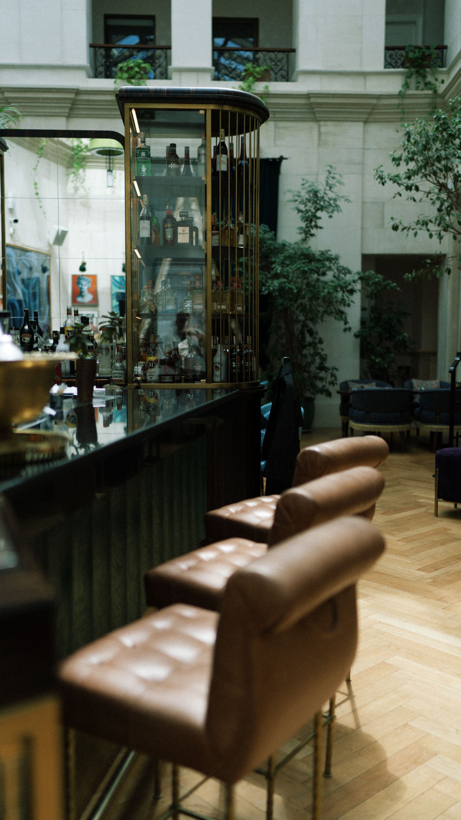 Warm hotel lounge bar with leather stools and brass bar cabinet